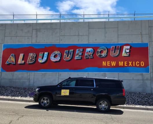 Four Winds Transportation Services SUV parked in front of the iconic ALBUQUERQUE NEW MEXICO mural — Native American & Latino owned, 13th-generation New Mexican family business serving ABQ Sunport transfers, corporate black car, and chauffeured transportation across New Mexico.